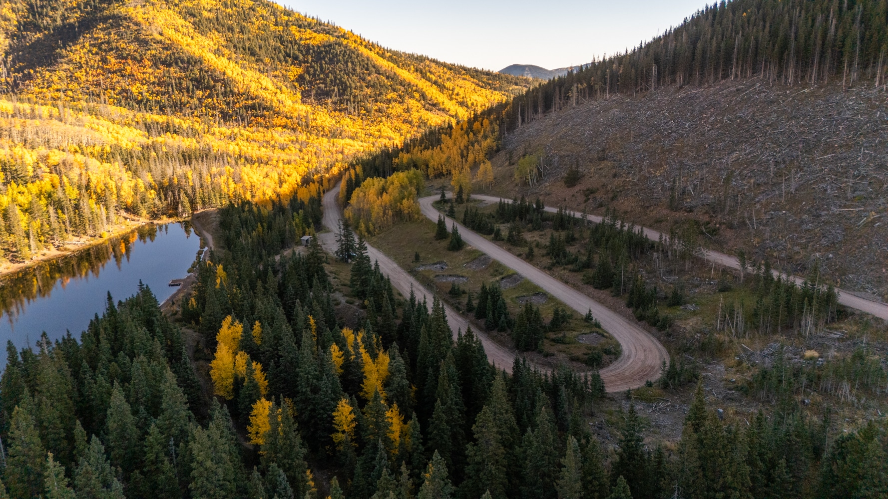 A mountain road winding through gold aspens beside a lake in Spanish Peaks Country